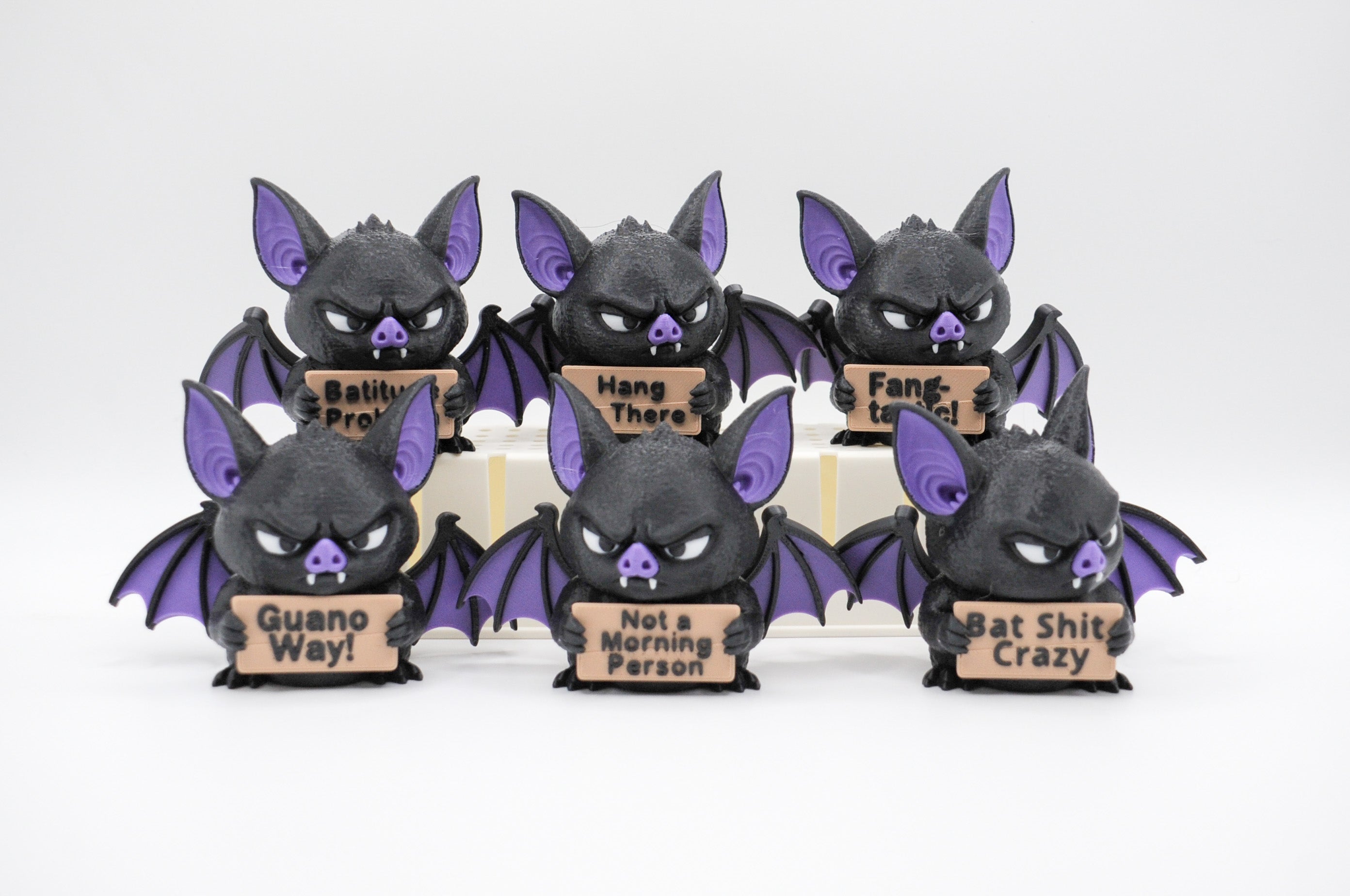 Group of bat figures holding six humorous signs