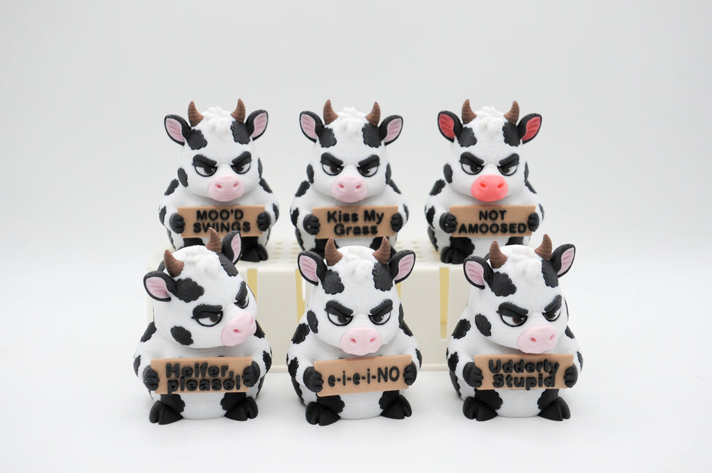 Group of cow figures holding six humorous signs
