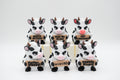 Group of cow figures holding six humorous signs
