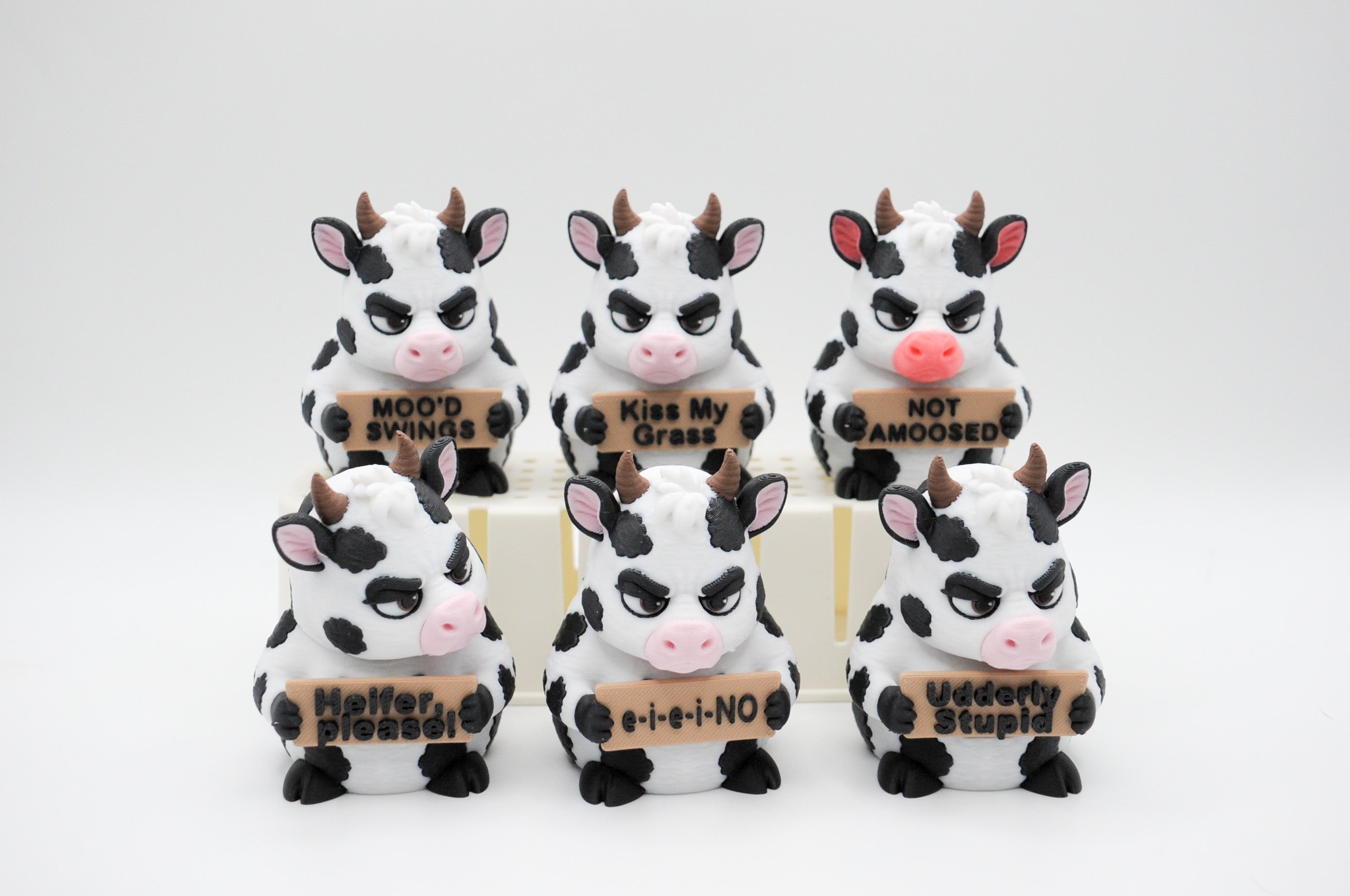 Group of cow figures holding six humorous signs