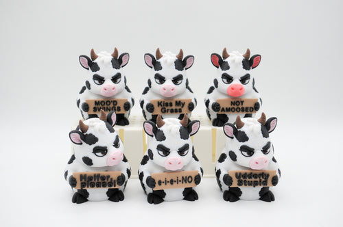 Group of cow figures holding six humorous signs