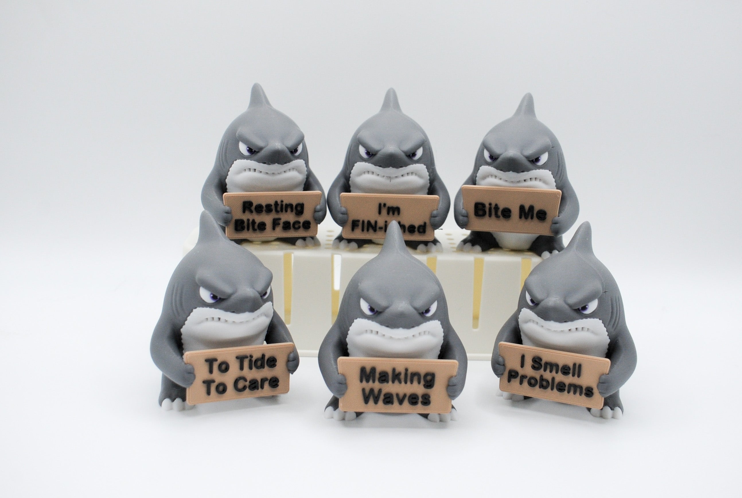 Group of shark figures holding six humorous signs
