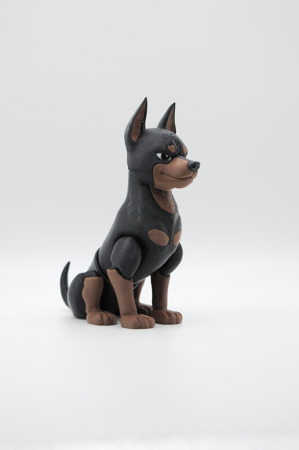 Portrait view of a seated black and tan Doberman figure