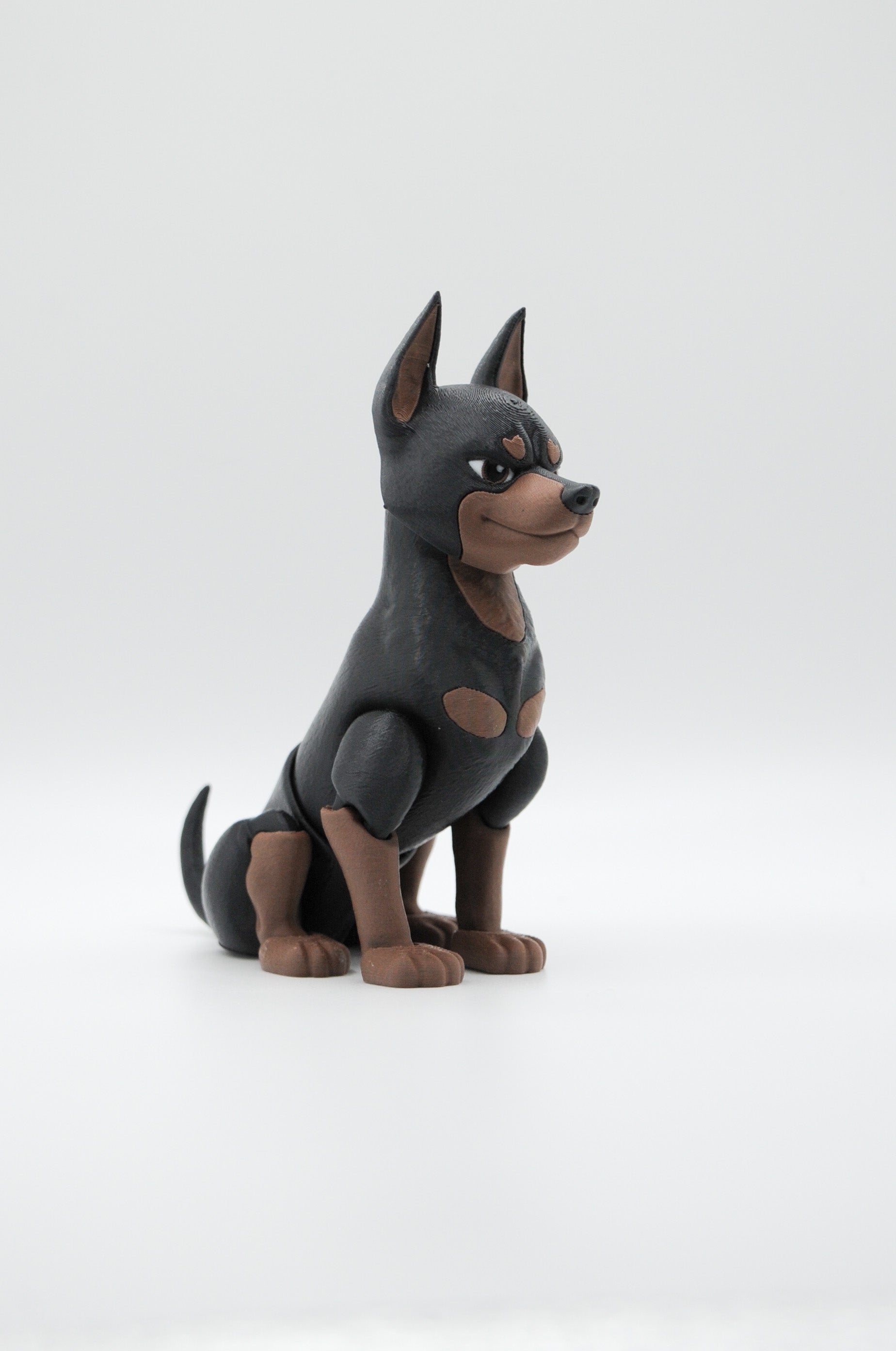 Portrait view of a seated black and tan Doberman figure