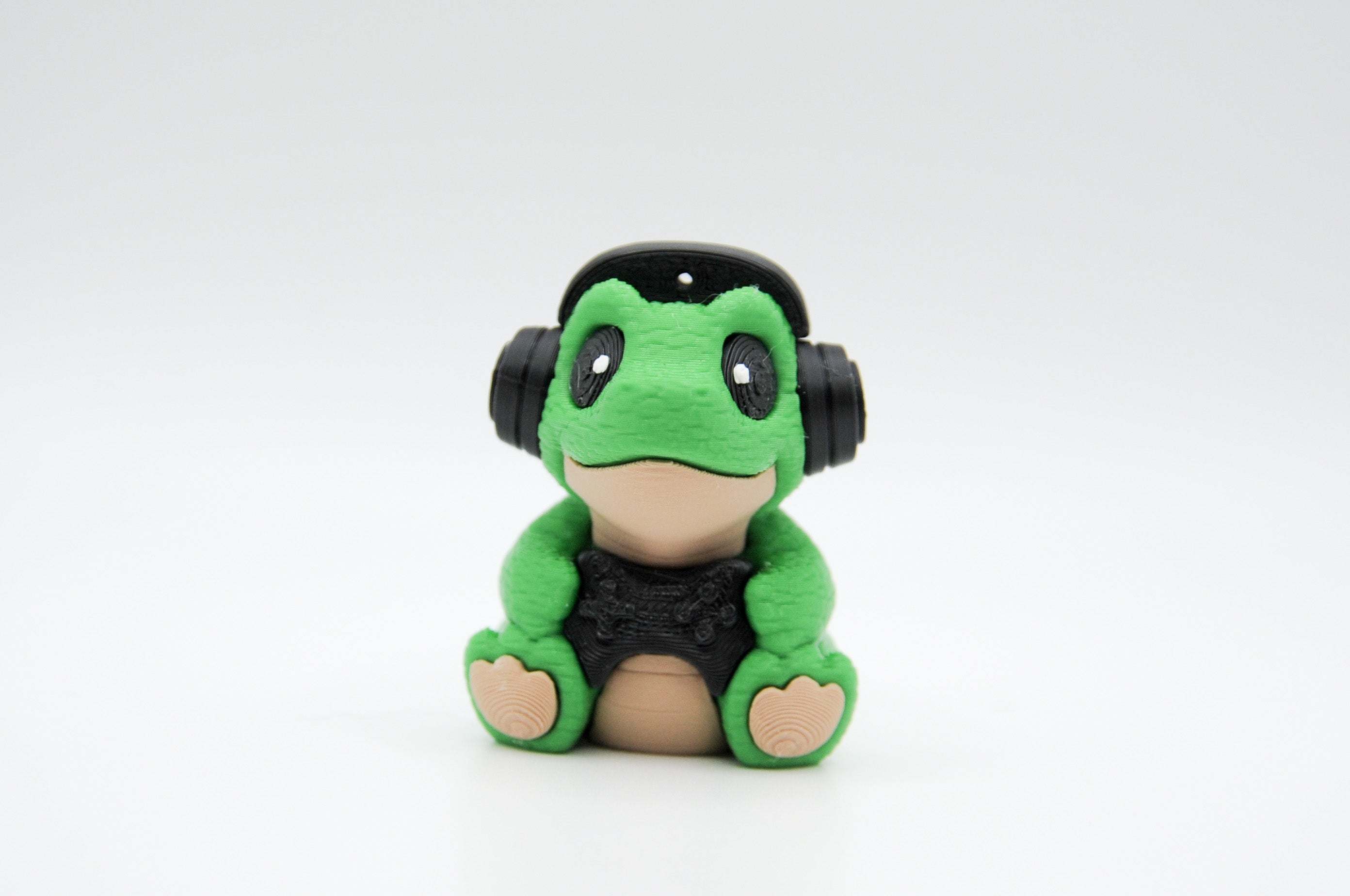 Seated green frog figure wearing large black headphones