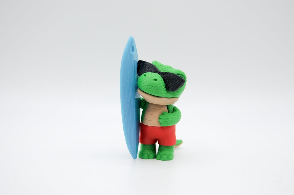 Green frog figure standing beside a blue surfboard