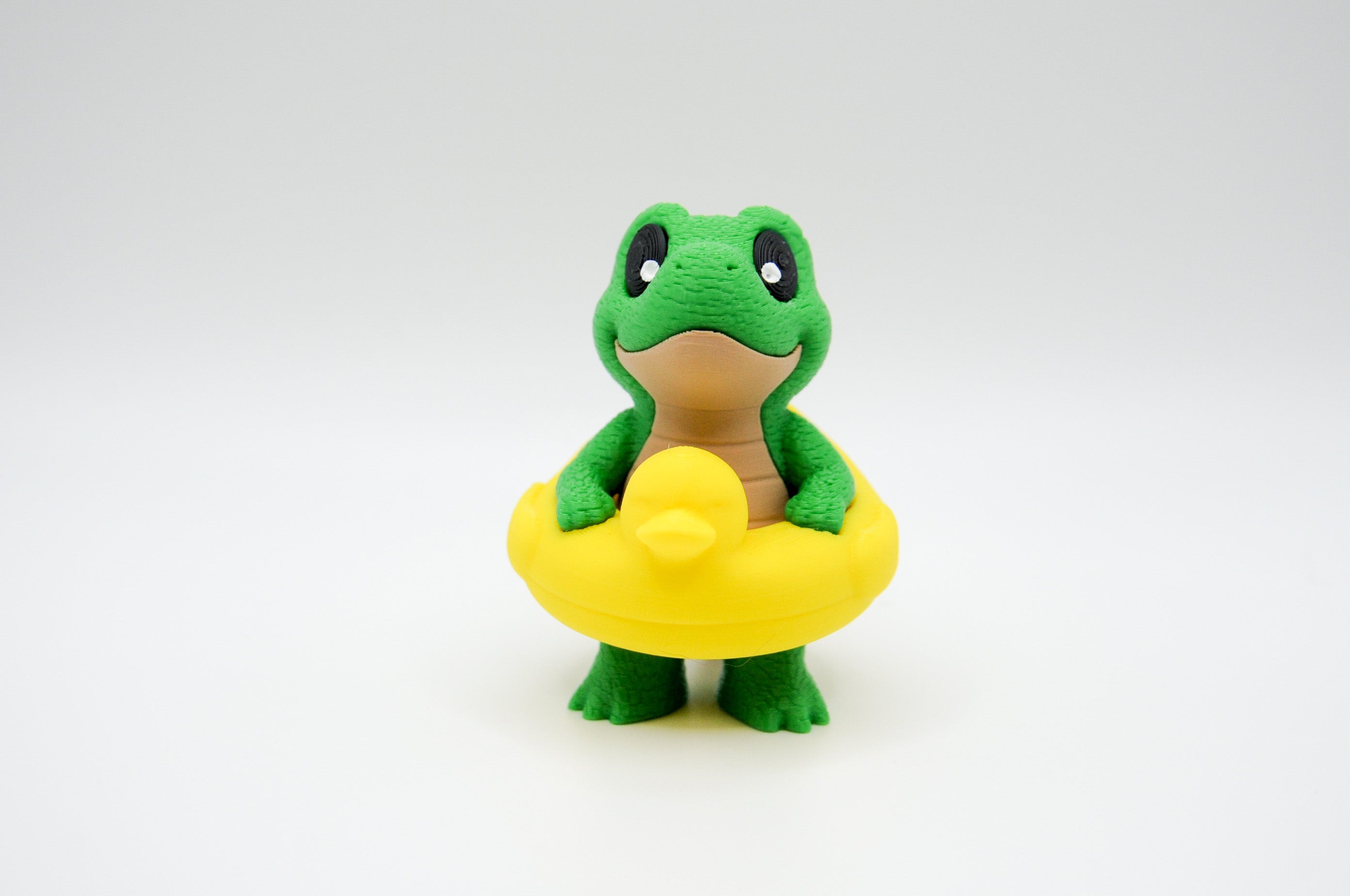 Green frog figure wearing a bright yellow swim ring