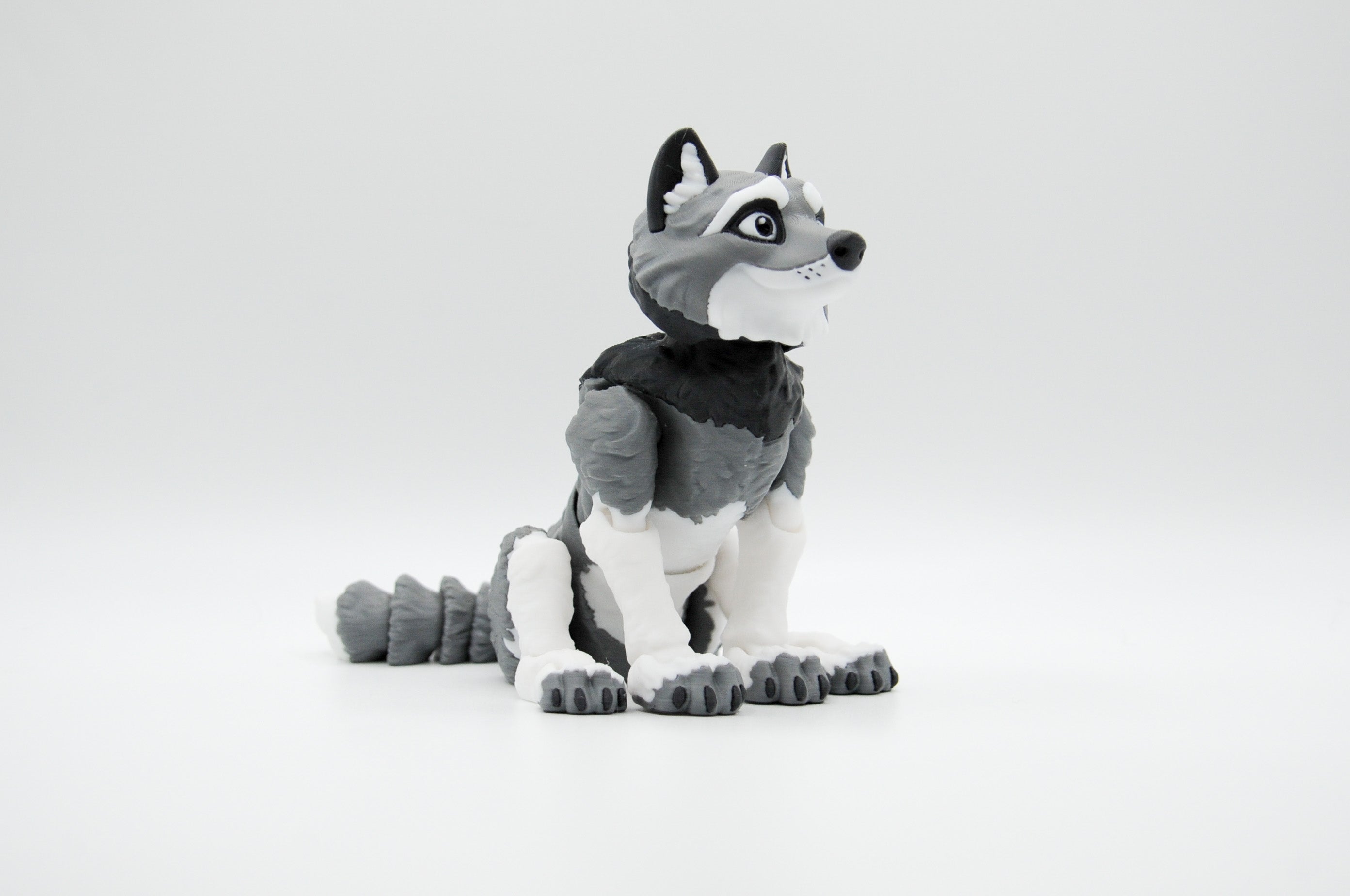 Gray and white wolf figure seated with tail curled beside it