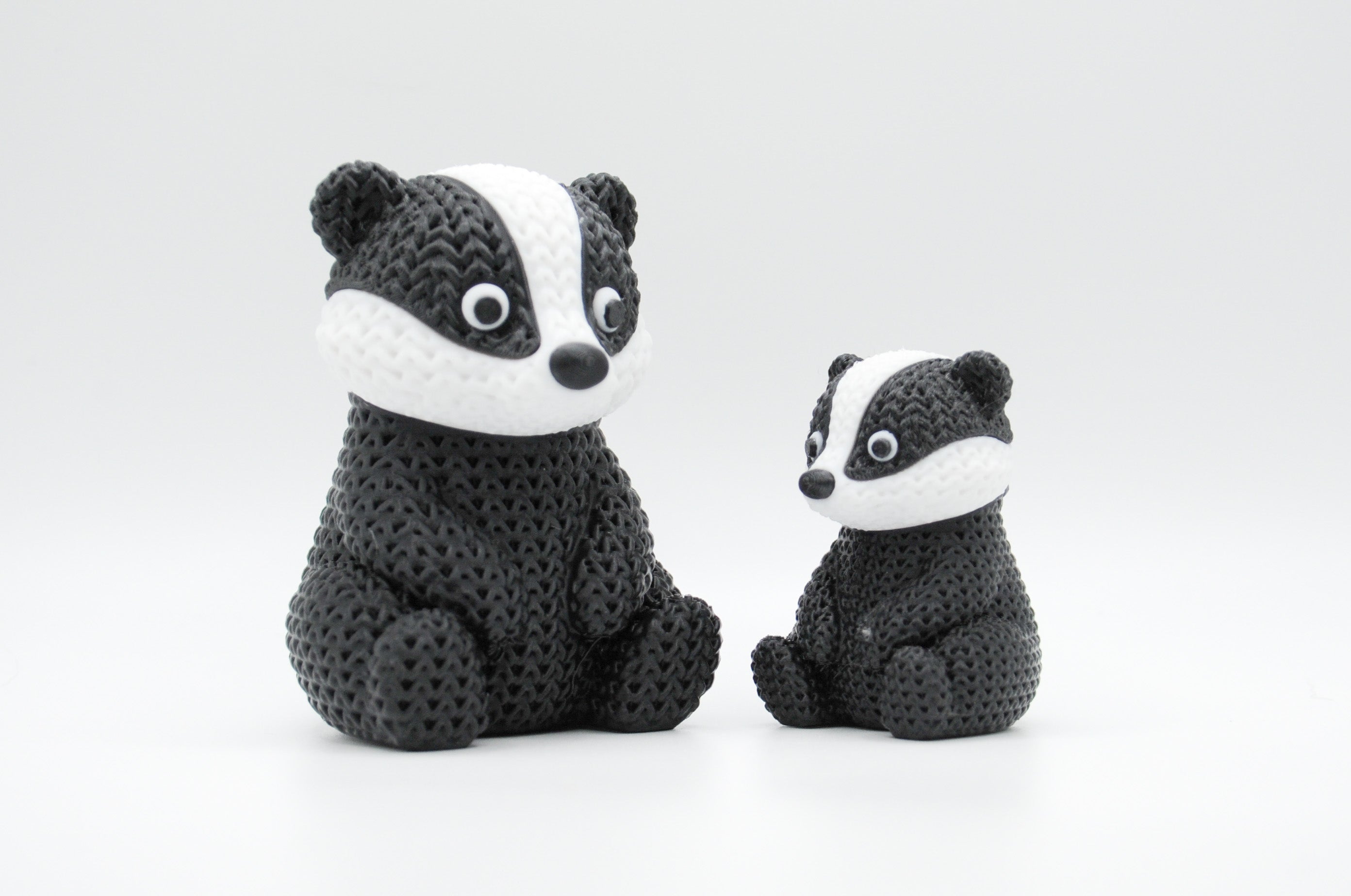 Black, white, and gray knitted-style badger figures in large and small sizes