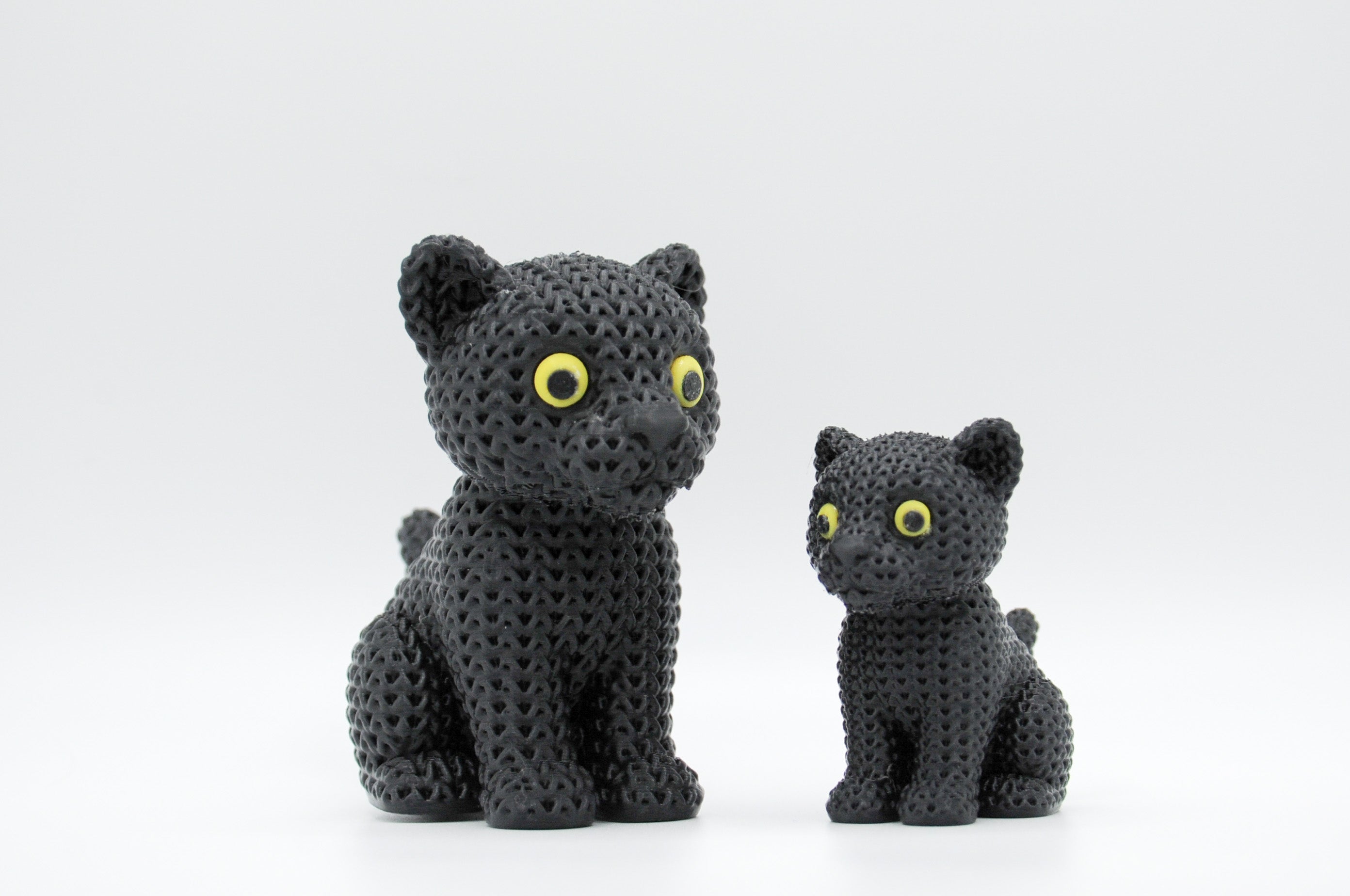 Black knitted-style cat figures with yellow-green eyes in large and small sizes