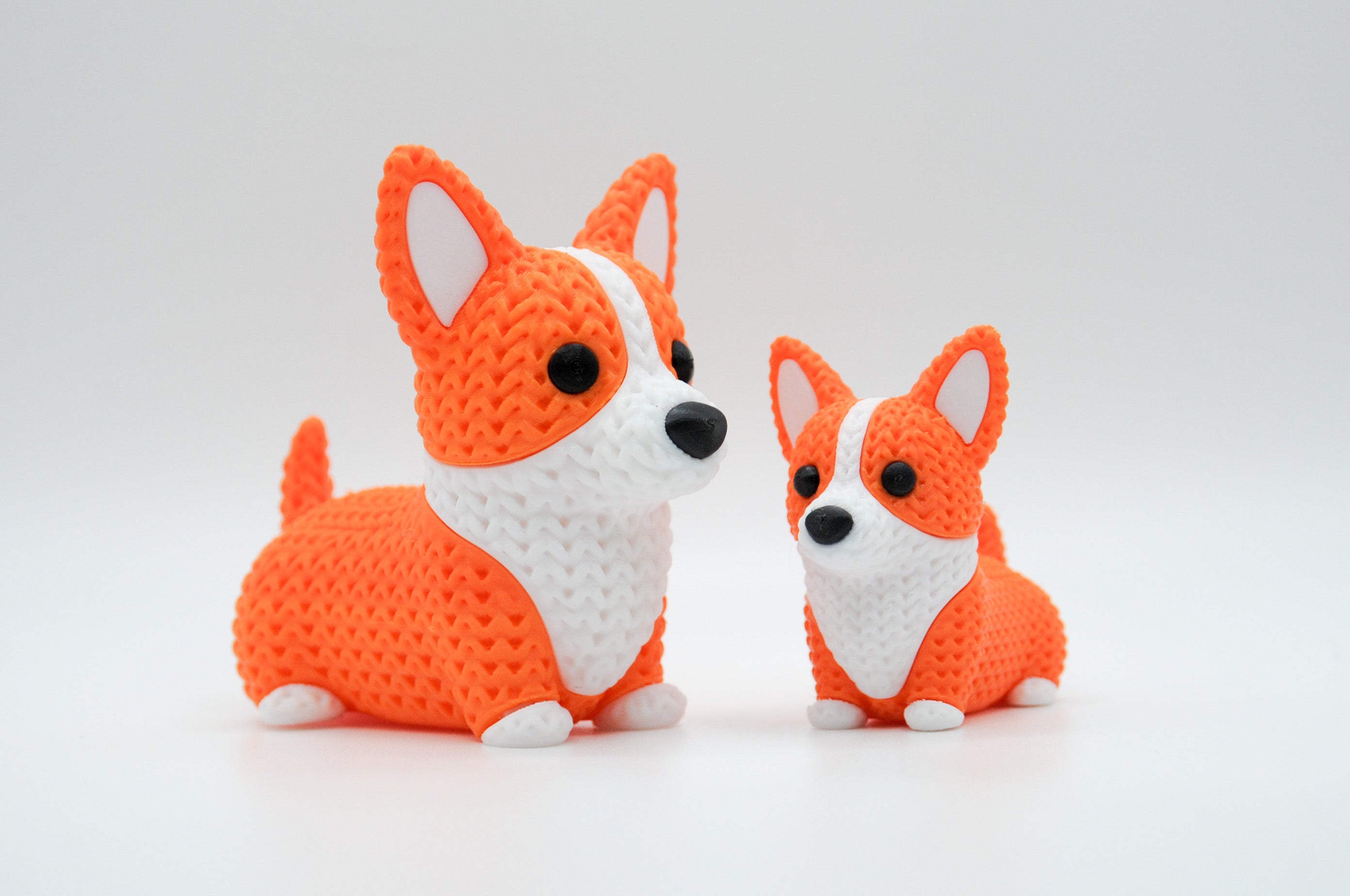 Orange and white knitted-style corgi figures in large and small sizes