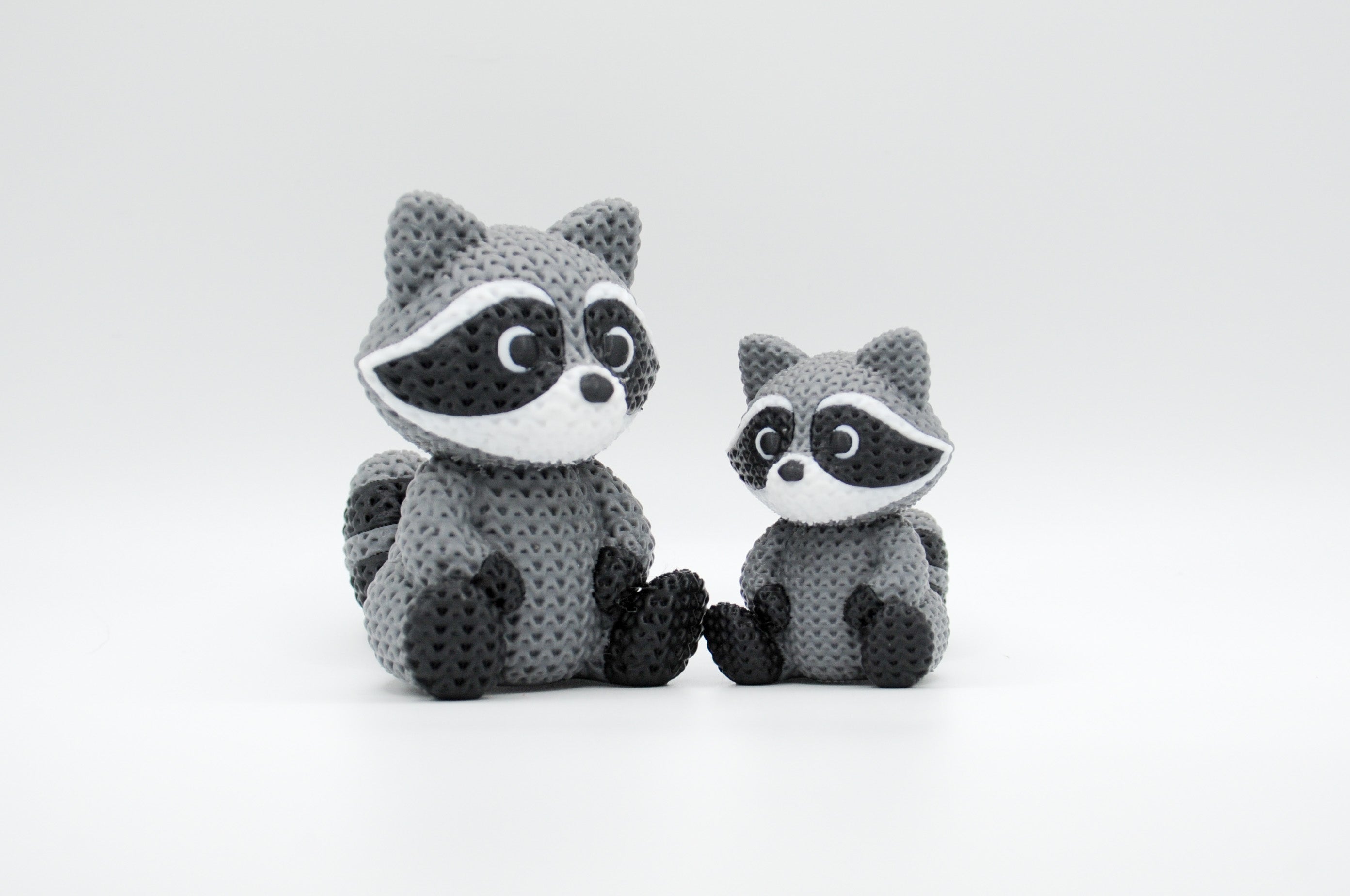 Gray knitted-style raccoon figures in large and small sizes