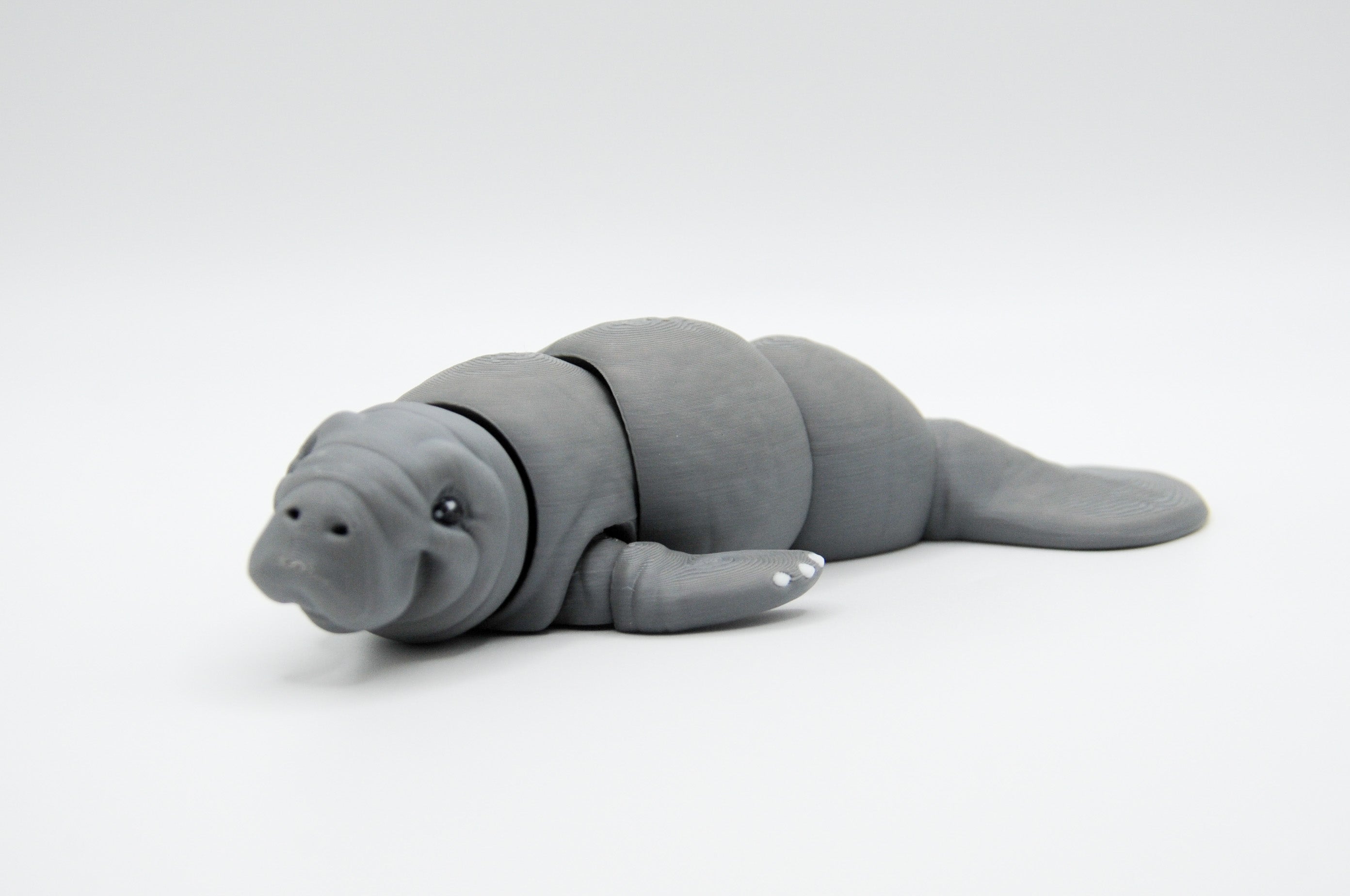 Gray manatee figure resting in a horizontal pose