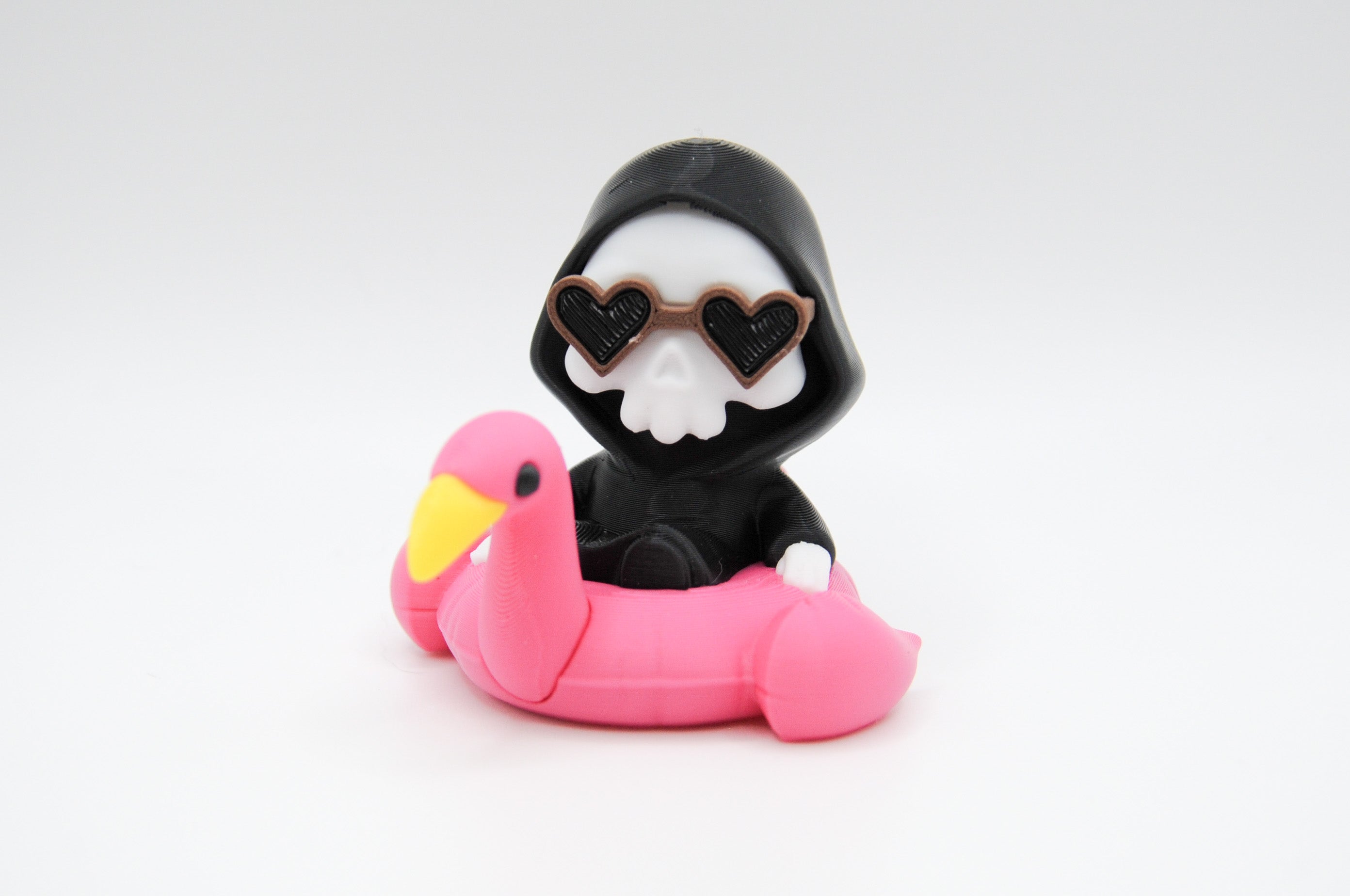Hooded reaper figure wearing heart sunglasses in a pink flamingo float