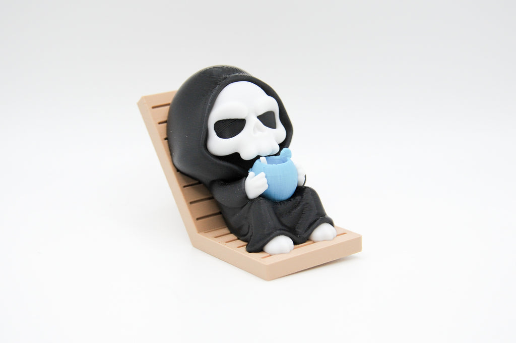 Hooded reaper figure reclining in a lounge chair with a blue drink