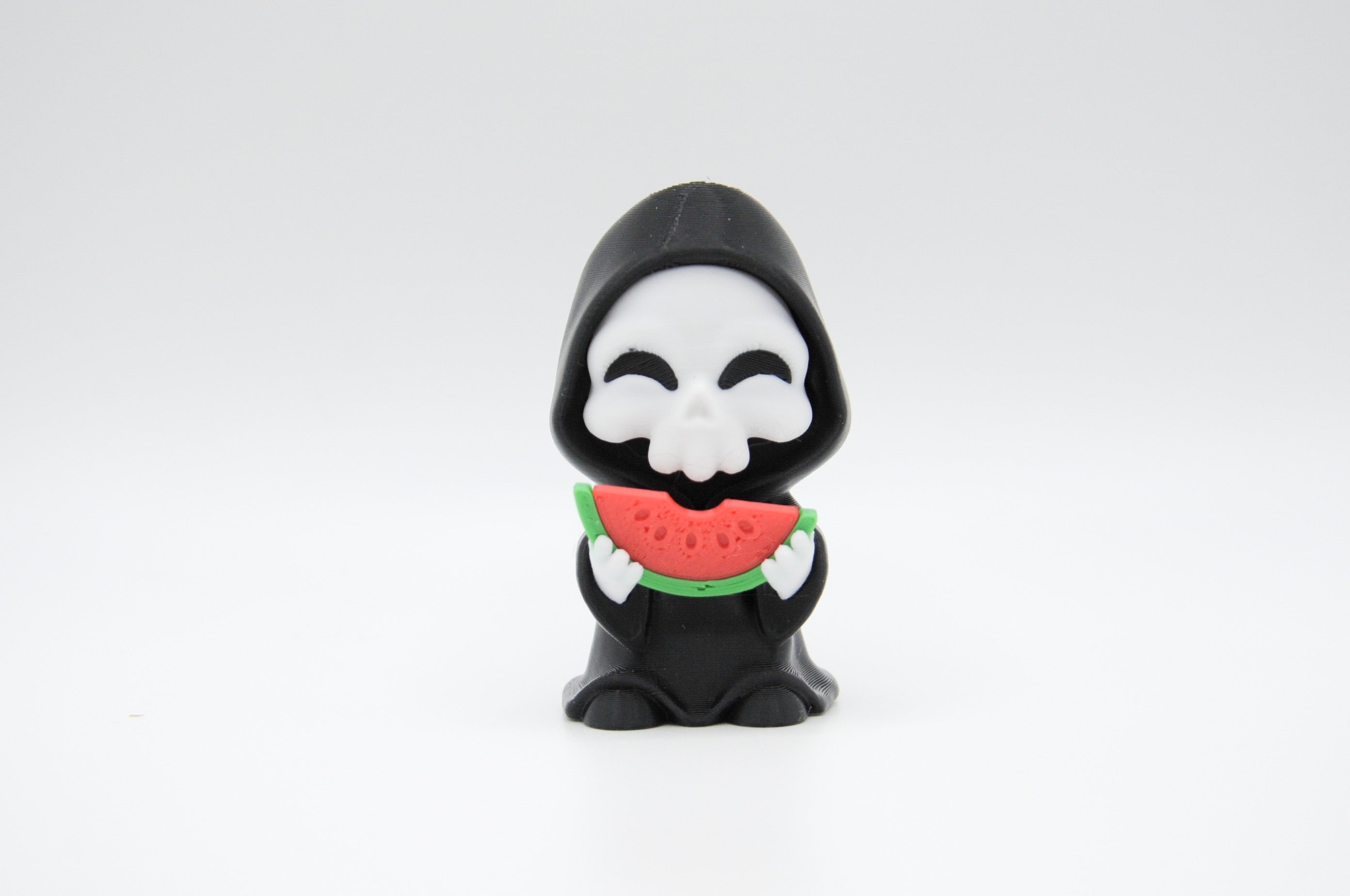 Hooded reaper figure eating a slice of watermelon