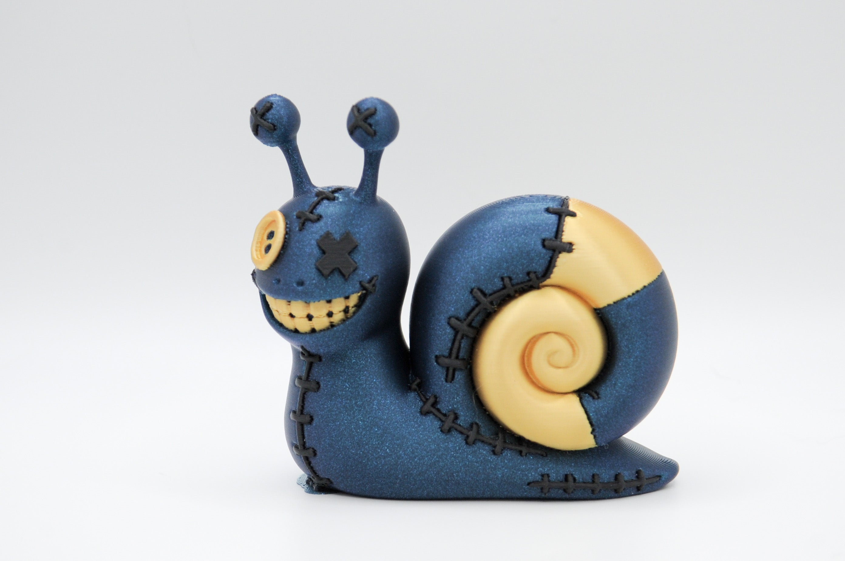 Dark blue stitched-style snail figure with a yellow spiral shell